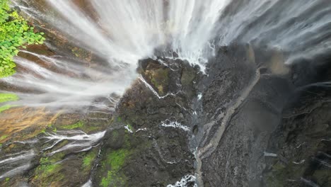 aerial looks down onto dramatic tumpak sewu waterfall grotto on java