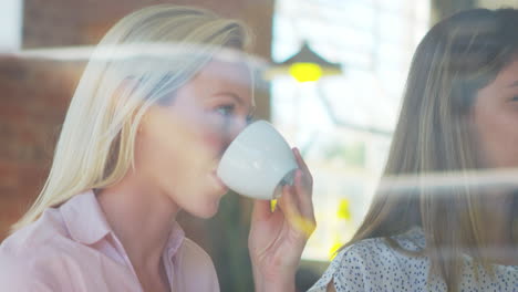 tres mujeres de negocios reunidas en una cafetería disparadas a través de la ventana