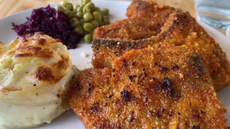 chuletas de cerdo fritas, puré de patatas y guisantes servidos en un restaurante en islandia con video en primer plano