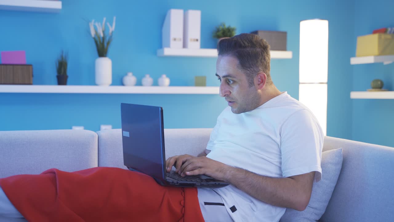 hombre acostado en la cama usando una computadora portátil confundido.