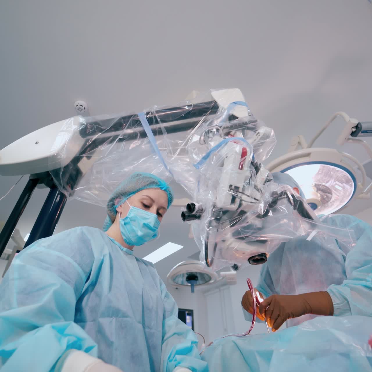 Neurosurgical procedure in operating room. Surgeon and assistant perform a neurosurgery through the modern microscope.