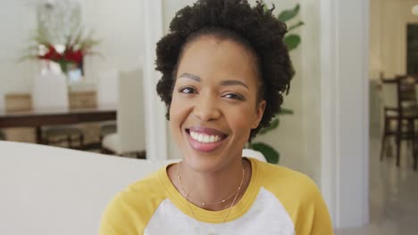 Porträt-Einer-Lächelnden-Afroamerikanischen-Frau,-Die-Im-Wohnzimmer-In-Die-Kamera-Blickt