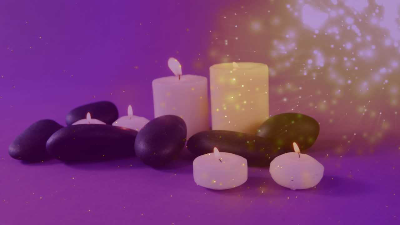 animación de luces que caen sobre velas y piedras de masaje sobre un fondo púrpura.