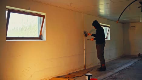 man painting interior room wall - wide shot