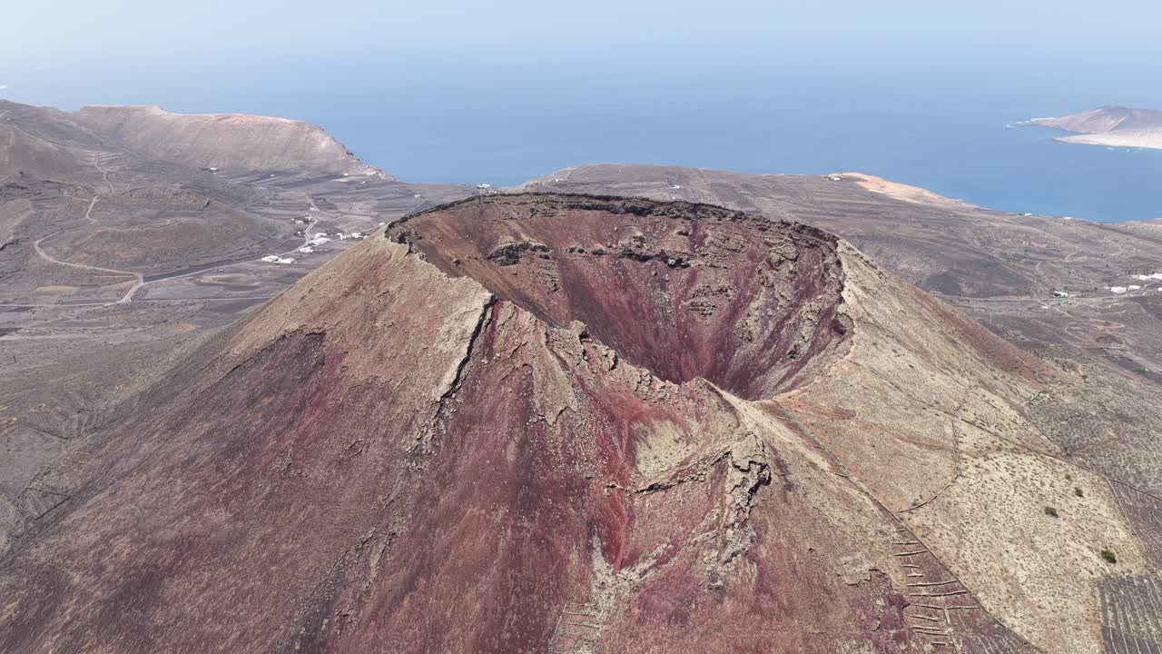 Aerial View Of Volcan de la Corona In Lanzarote, Spain, Overlooking Volcanic Terrain And Atlantic Ocean. descending tilt-up shot