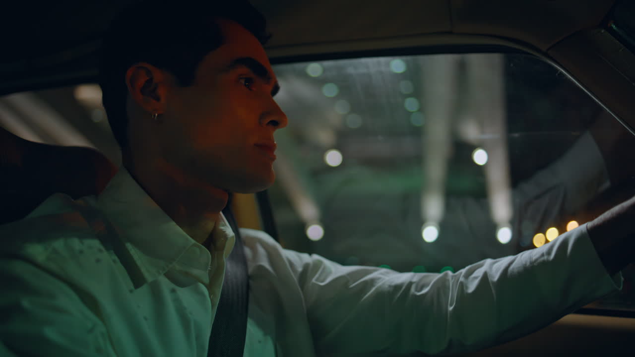 클로즈업 사업가 차를 타고 밤 도로. 남자 운전자가 스티어링 을 회전