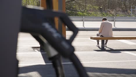 man waiting and sitting on the bench at charging station under the sun