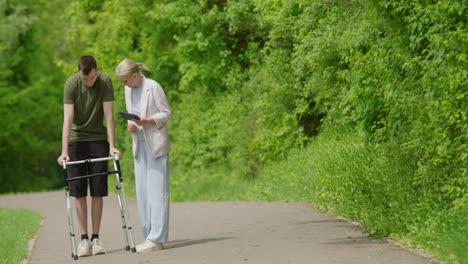 person with a walker receiving assistance in a park.