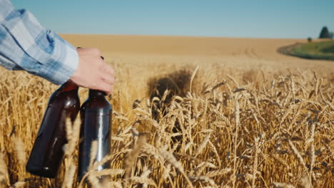 a man with two bottles of beer walks along a wheat field