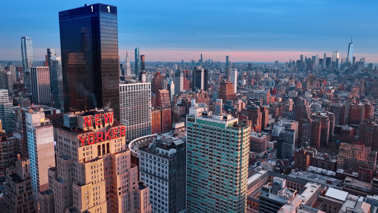 New York, USA, 15. april 2026: New Yorker Hotel takskilt ved solnedgang. Luftfoto av New Yorker Hotel-skilt med Midtown Manhattan skyline og One World Trade Center i skumringen