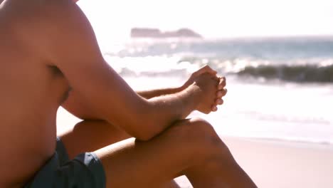 Surfer-watching-the-ocean-and-sitting-on-his-board