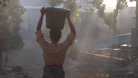 Asian-Woman-Walking-Barefoot-While-Carrying-Water-Bucket-On-Head---Static-Shot