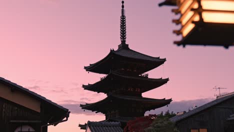the yasaka pagoda in kyoto stands beautifully illuminated by the warm hues of the setting sun, casting its tranquil silhouette against the sky.