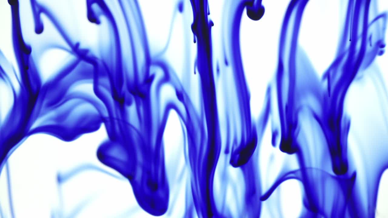Colorful chemical liquids mix and swirl in water, forming smooth abstract patterns and organic shapes
