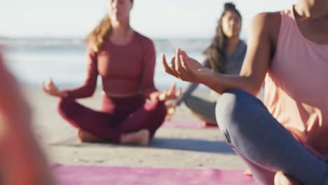 Group-of-diverse-female-friends-meditating-at-the-beach