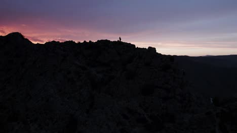 sunset over mountain peaks with hikers