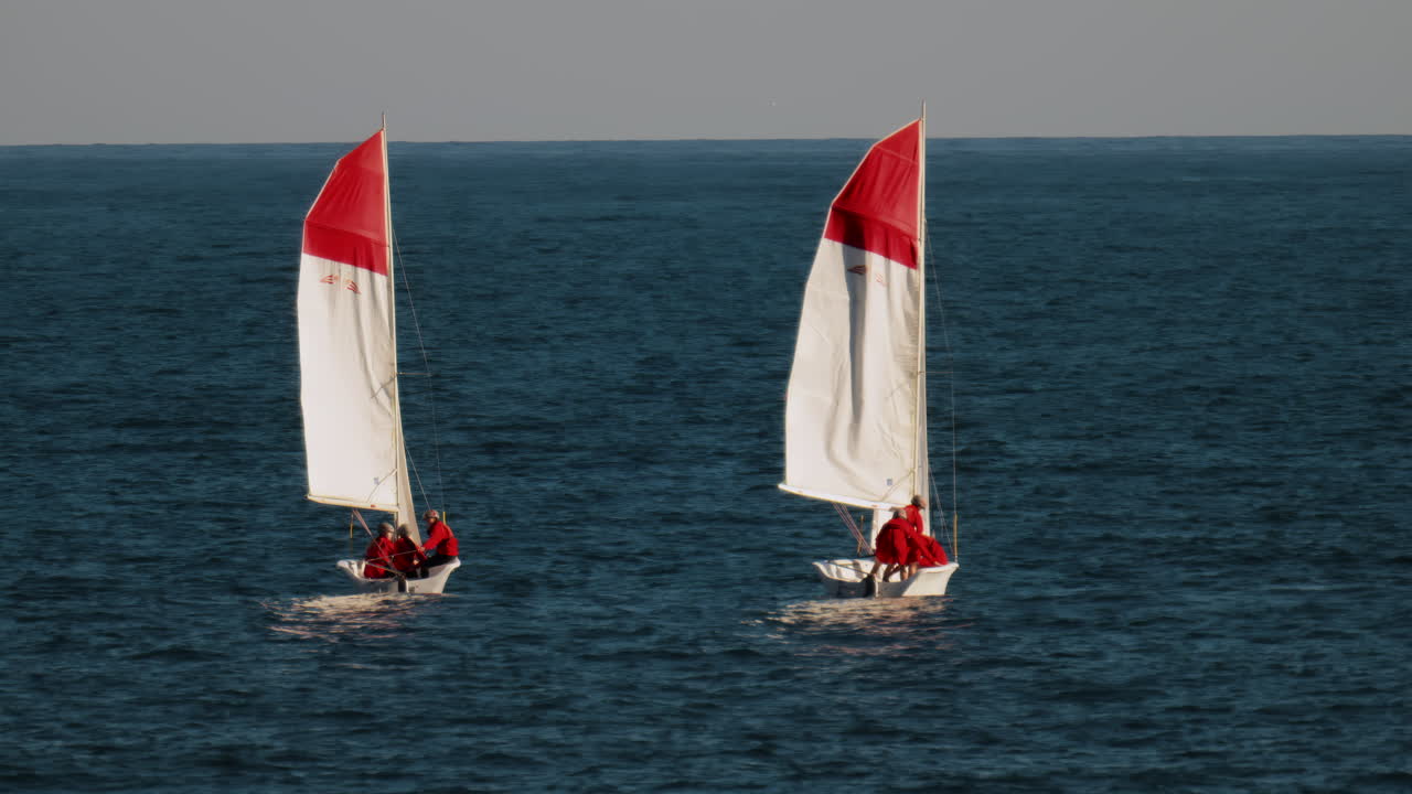 La Condamine, Monaco - February 8, 2025: Sailboats with red and white sails with people dressed in red uniforms