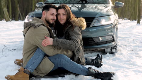 pareja caucásica abrazándose en la nieve durante un viaje por carretera.