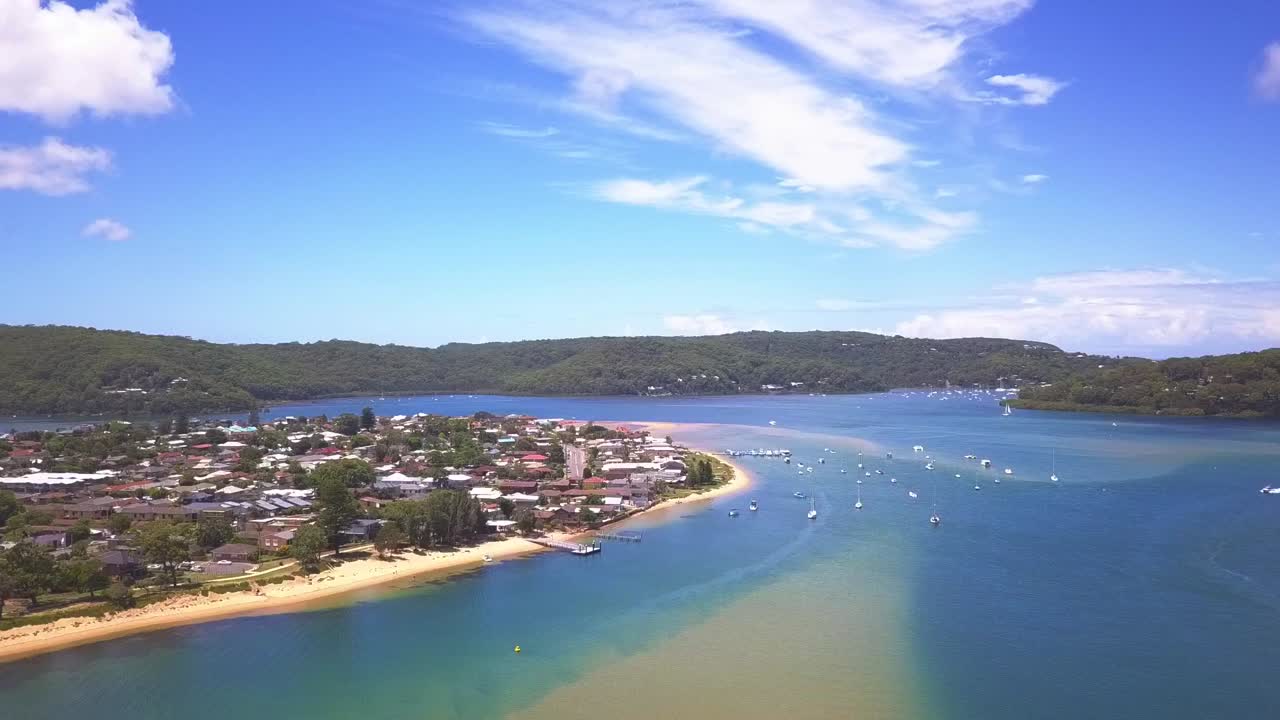 Aerial view tropical paradise beach turquoise water, white sand and blue sky with waterfront luxury houses. Slow ascending drone shot.