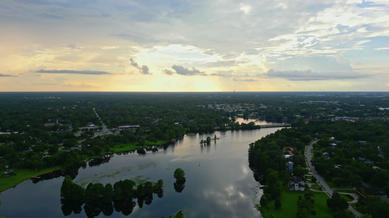 Aerial establishing over Hillsborough River with distant Tampa skyline under evening clouds reflection in water, panoramic of Florida suburb