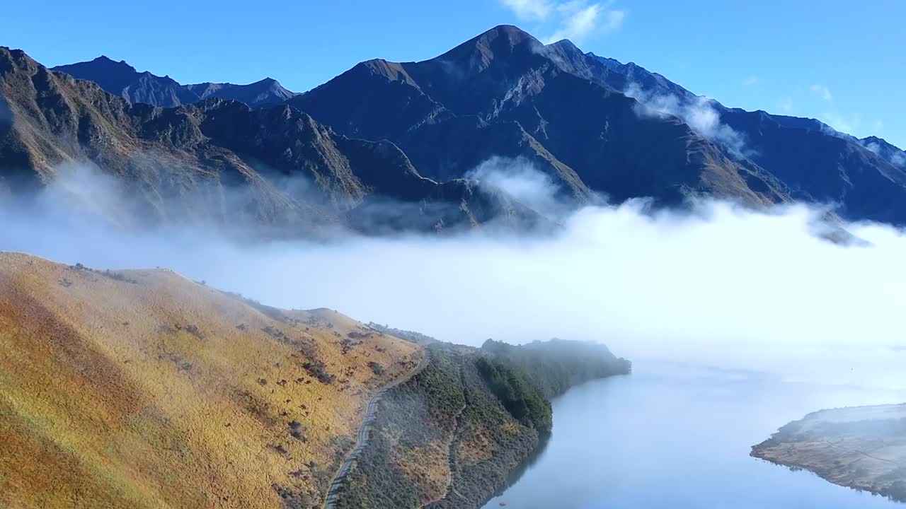 Perspectiva aérea impressionante de nuvens baixas sobre um lago tranquilo cercado por picos de montanhas acidentadas