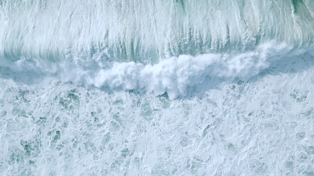 vista aérea de las olas blancas y espumosas que ruedan en la costa de nazare, portugal