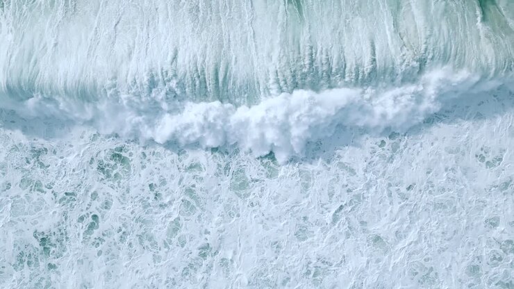 Overhead View Of White Foamy Waves Rolling In The Coast Of Nazare, Portugal