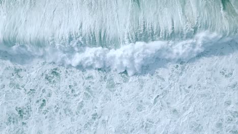 overhead view of white foamy waves rolling in the coast of nazare, portugal