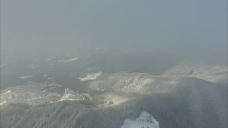 Drohnen-Reverse-Dolly-über-Nebligen-Wolken-Auf-Einem-Kalten,-Schneebedeckten-Berg