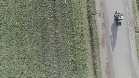 drone shot motorcyclist driving on farm roads from above