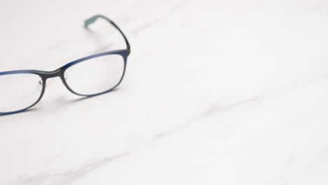 close-up shot panning and revealing a pair of eyeglasses that is placed on a table