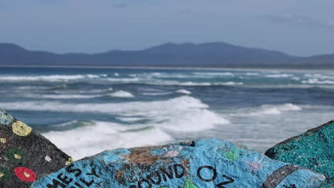 waves crash against colorful rocks on shore