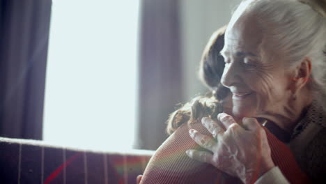 elderly woman hugging granddaughter and smiling in sunlit living room