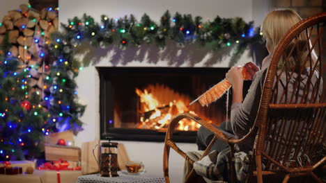 descansar en una noche de invierno - una mujer teje sentada junto a una chimenea decorada para navidad