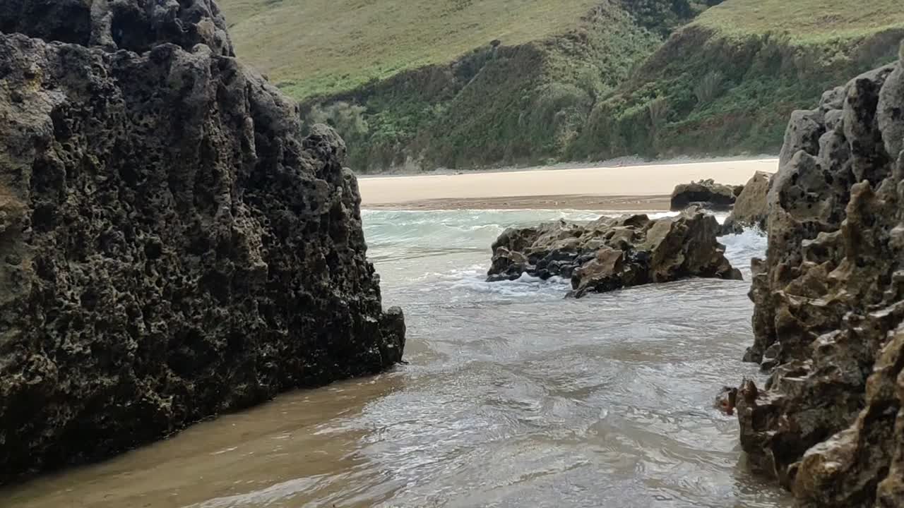 Waves splash between rocky cliffs at Torimbia beach, Asturias, wild and peaceful coast