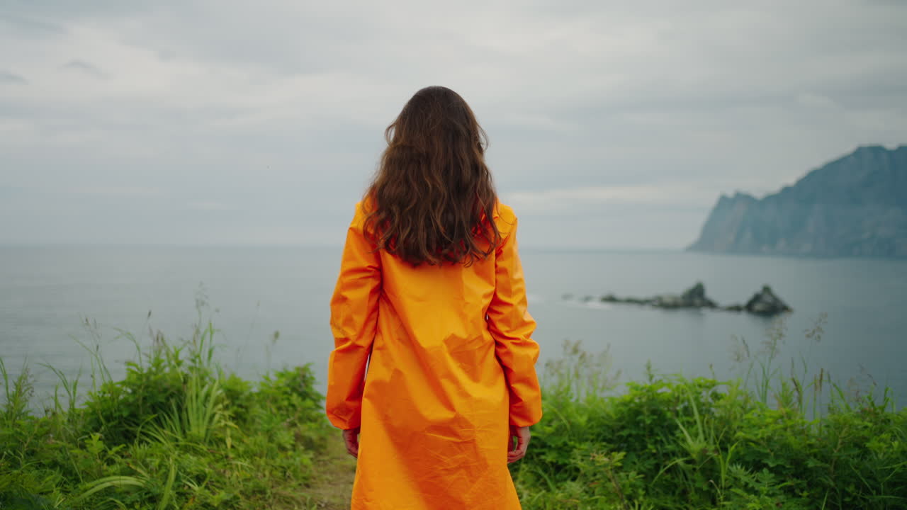 Woman in Orange Raincoat by the Sea
