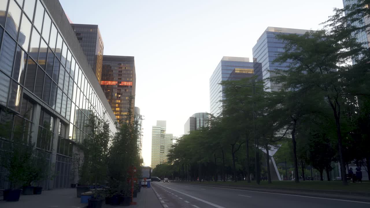 Brussels Nord urban setting with high glass business buildings, during sunrise in the summer with a car coming in the distance. Close to the Brussels north train station.