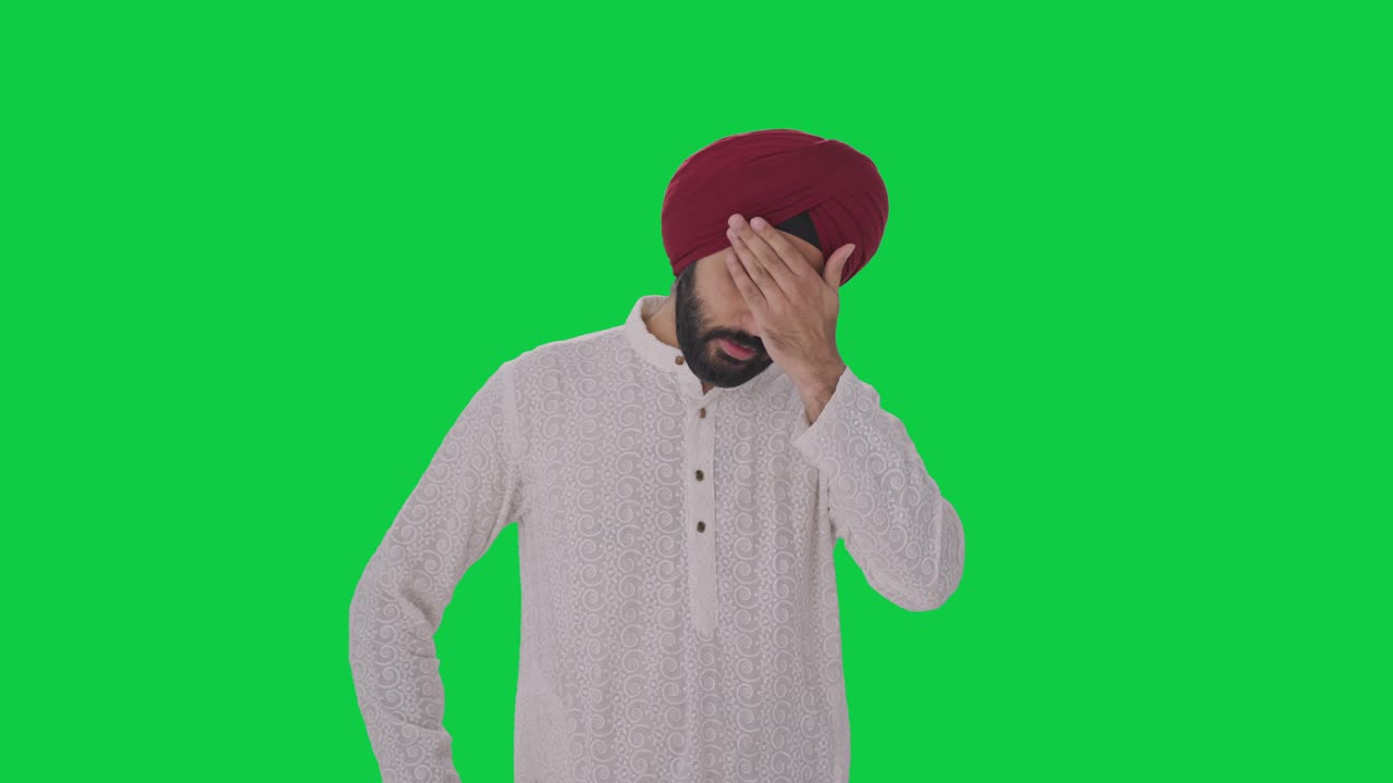 Uomo indiano Sikh con mal di testa su green screen