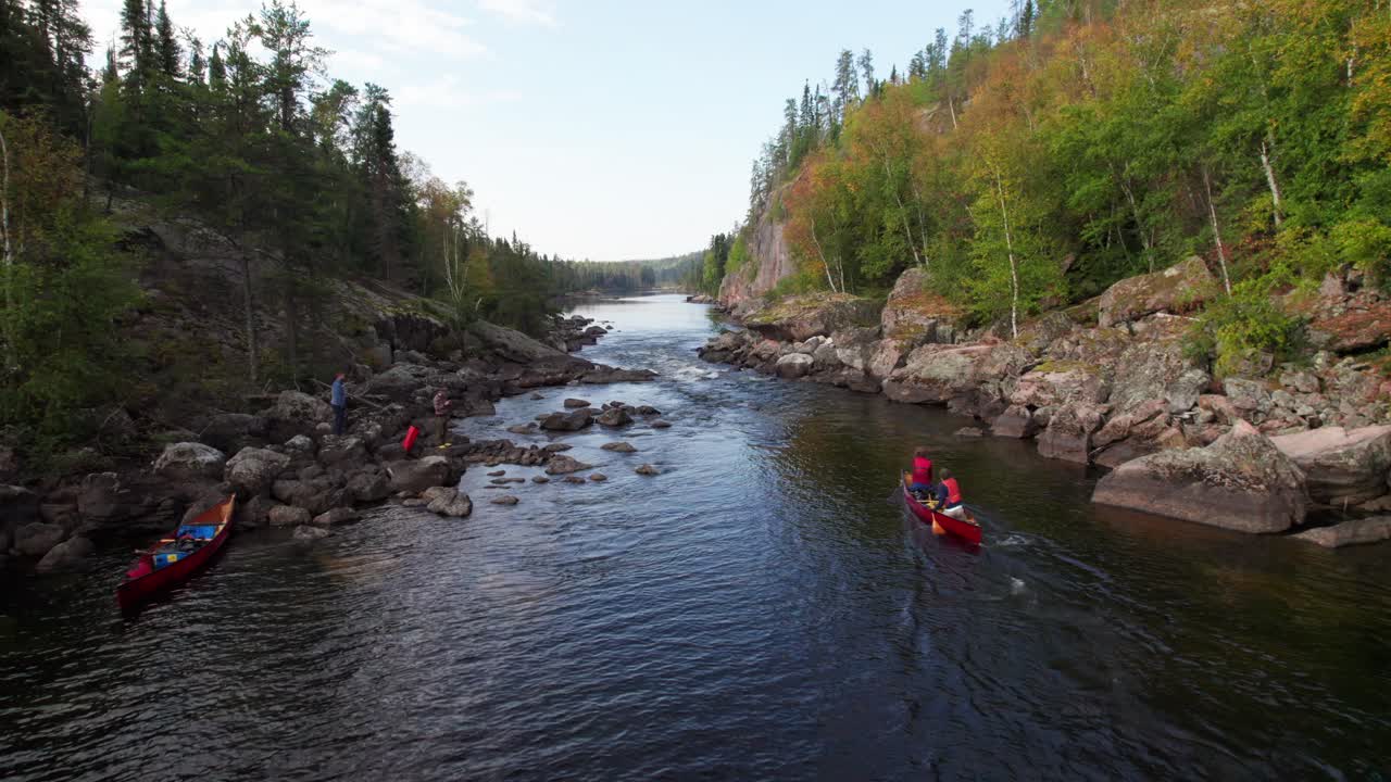 Epic long aerial of canoe shooting whitewater rapids, reversing out to reveal gorgeous river stretching to horizon