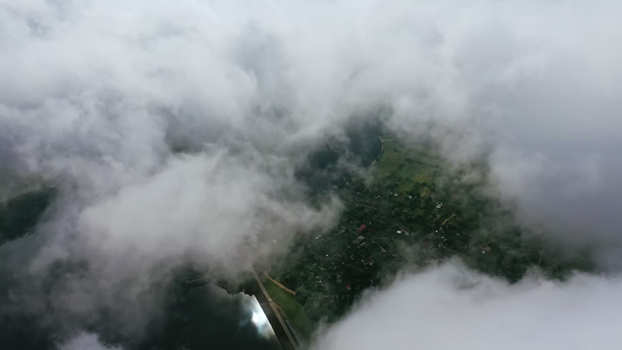 Light clouds moving in the sky. City view from the air through white clouds. Flying over the river and country. Aerial view.