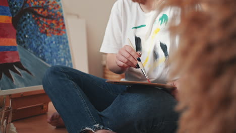 an unrecognizable woman mixing colors on a painter's palette