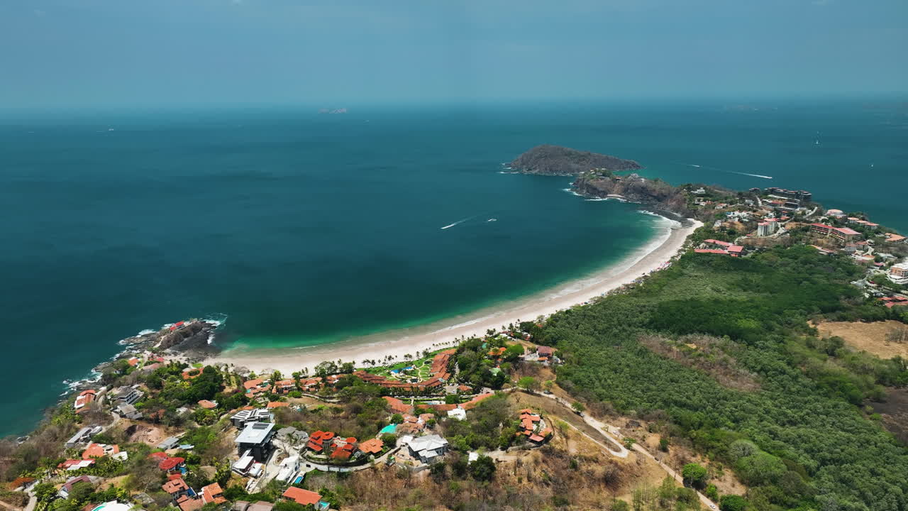 Aerial view of a stunning tropical beach bay with resorts and lush green hills