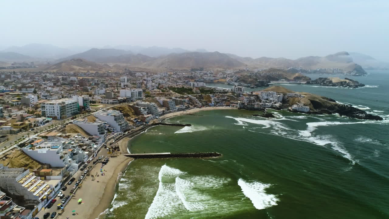 volando hacia atrás a lo largo de la costa de san bartolo, día brumoso en perú - vista aérea