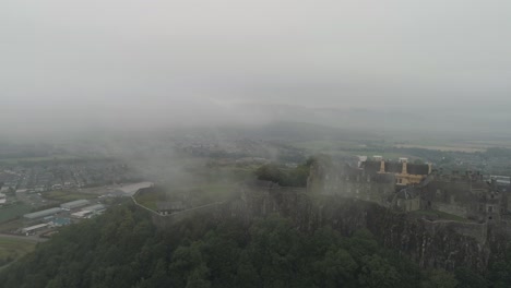 Aerial-pan-and-orbit-of-Stirling-Castle,-flying-West-to-East-through-low-lying-clouds