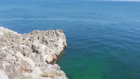 Una-Persona-Saltando-Al-Agua-Desde-Un-Acantilado-En-Portugal