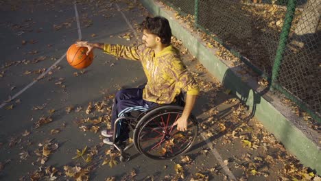 un adolescente discapacitado decidido jugando al baloncesto al aire libre en cámara lenta.