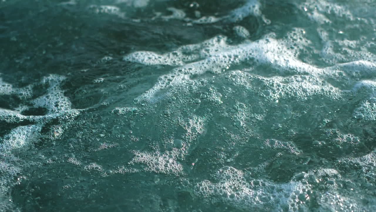 Bolle d'aria che creano schiuma sulla superficie del mare.