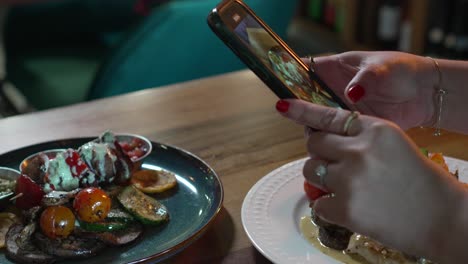 manos de una mujer fotografiando comida apetitosa con su teléfono inteligente