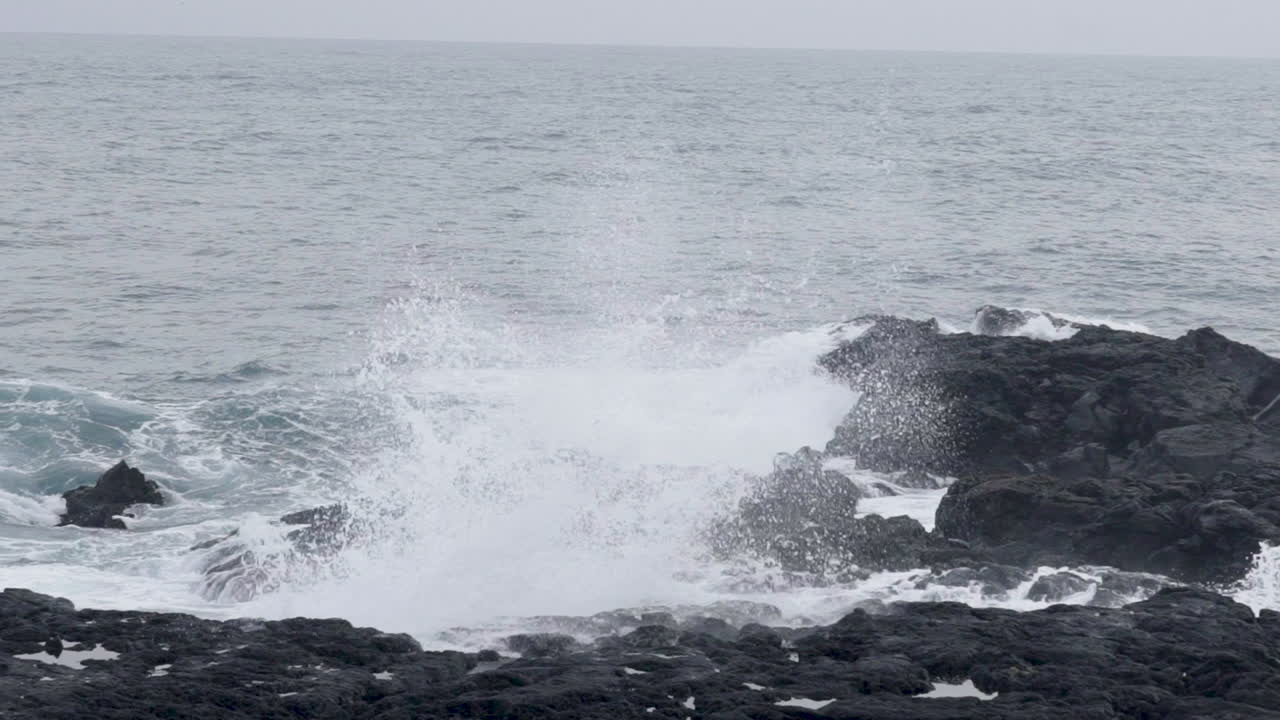 아이슬란드의 검은 바위 해안에서 파도가 터지고 있습니다.