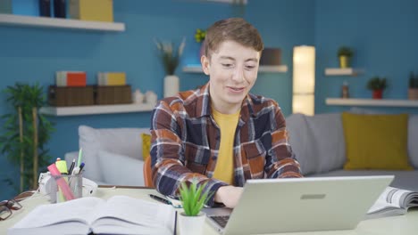 el estudiante que está en casa mira la computadora portátil y se alegra.